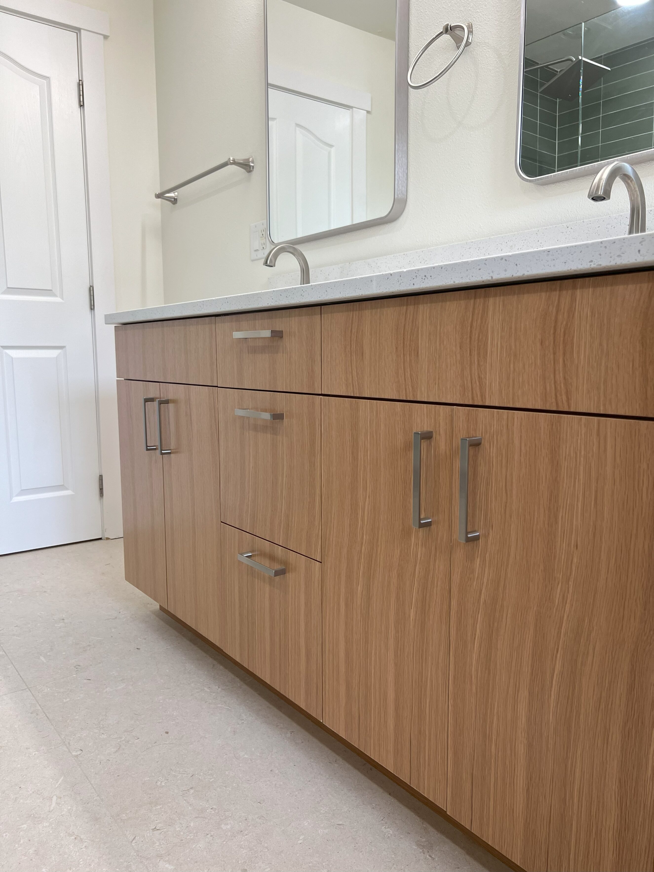 Modern bathroom vanity with light wood grain semi-custom cabinets, quartz countertop, dual undermount sinks with brushed nickel faucets and rectangular mirrors, staged for kitchen & bath remodel design services
